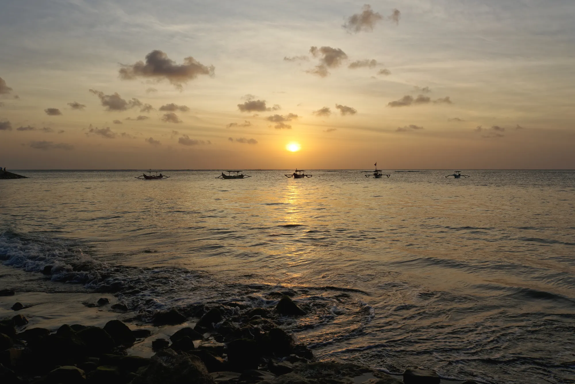Sunset off Kuta beach, jukung outriggers moored in silhouette on the water