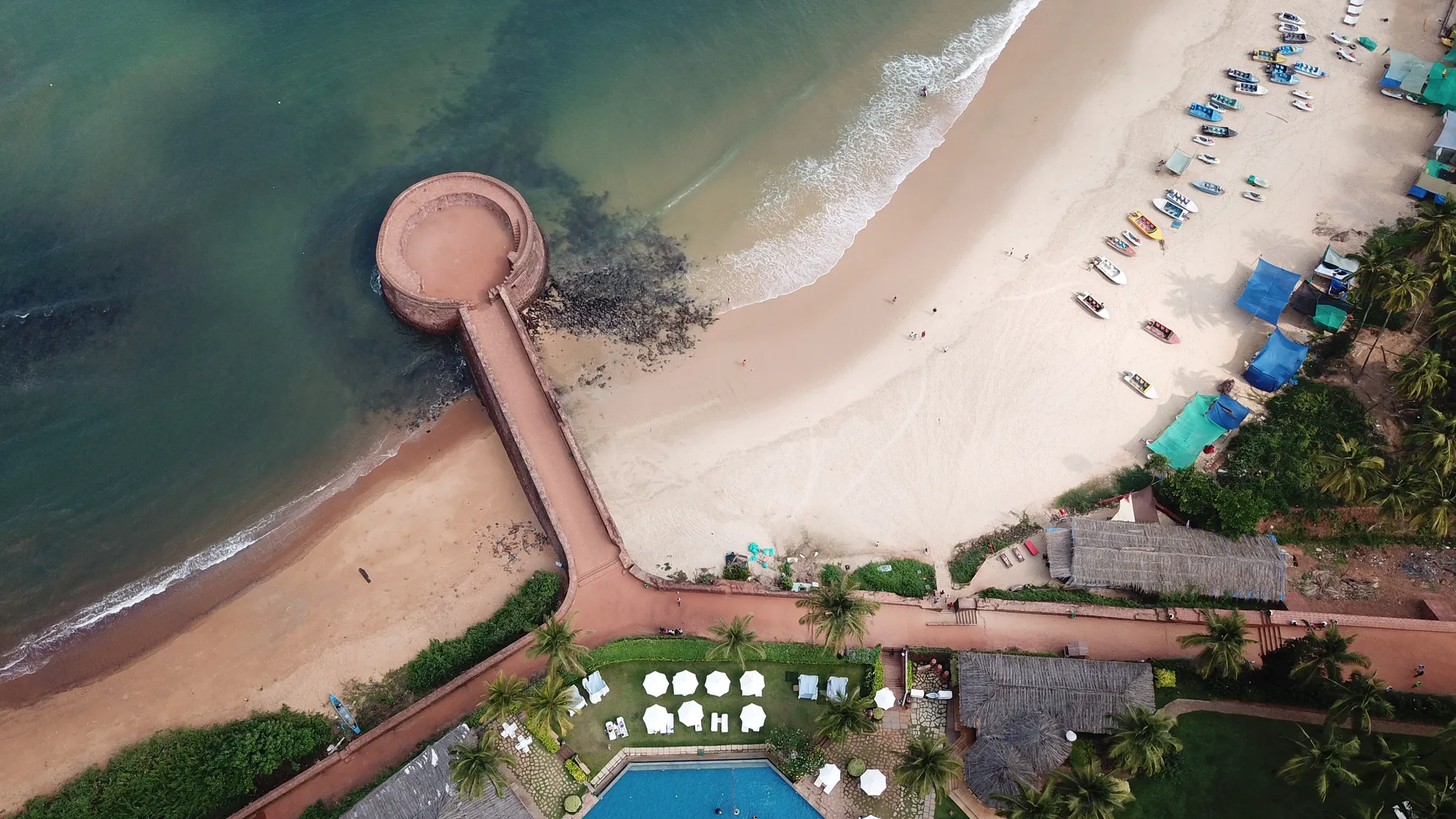 The round sea bastion of Fort Aguada and its wall running down to Sinquerim beach, from above
