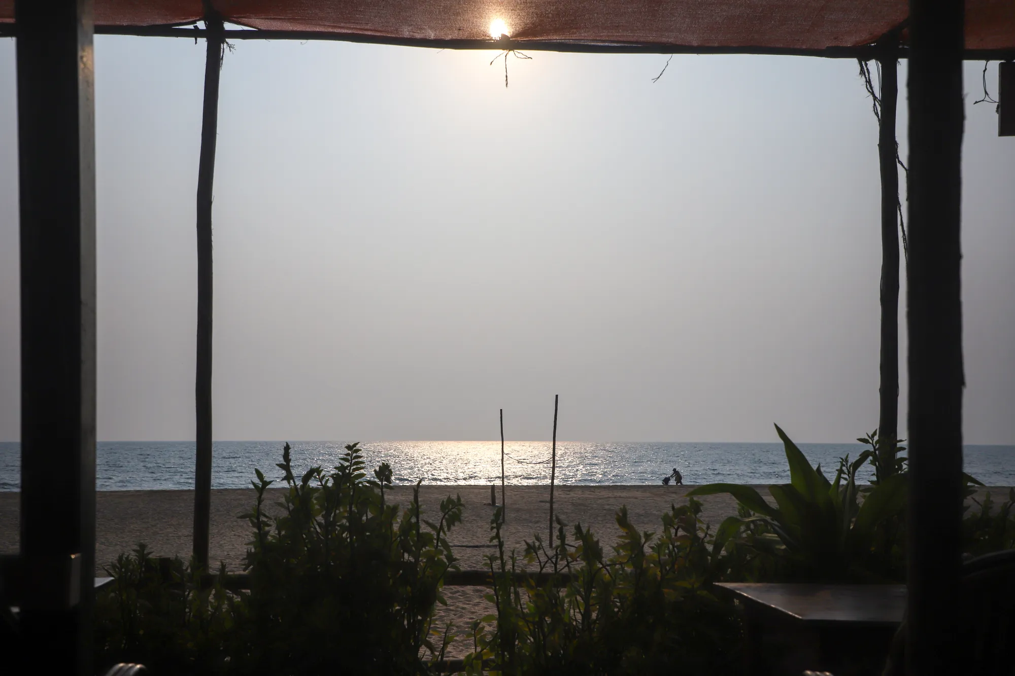 Sunset over the sea seen out from under the roof of a Palolem beach shack