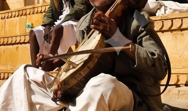 Two folk musicians in turbans playing a bowed string instrument