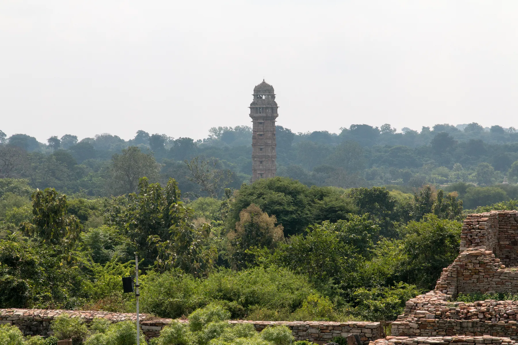 A tall carved victory tower among fort ruins
